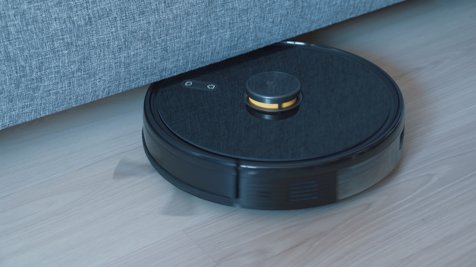 A black robot vacuum cleaner on a wooden floor